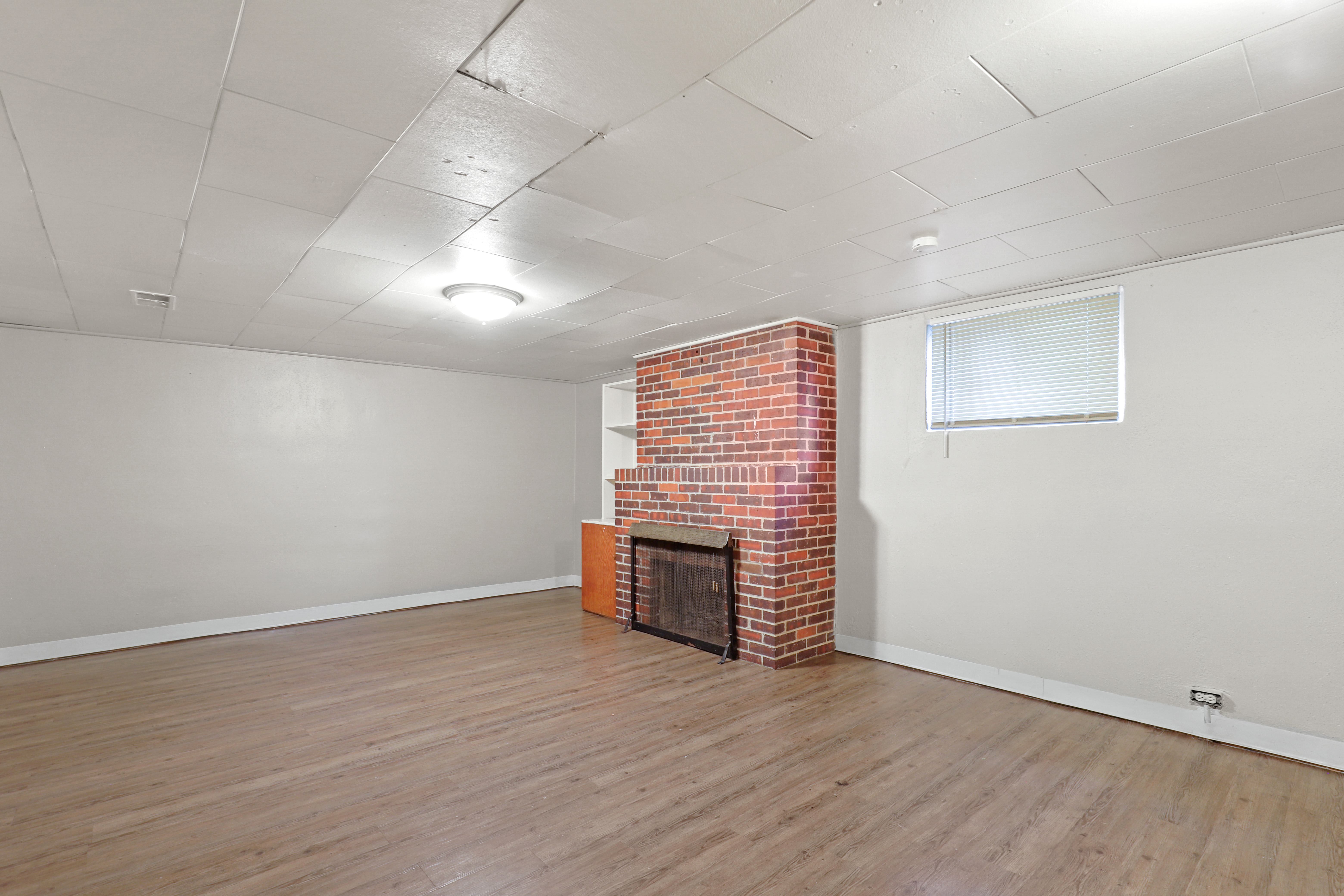 the living room of an empty house with a brick fireplace